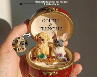 May include: A handcrafted polymer clay ring box with a pet figurine set. The red box contains two dog figurines, a golden retriever and a French bulldog, with two rings. The box is open, revealing the text "GOLDIE & FRENCHIE".