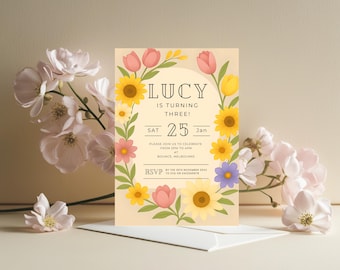 Puede incluir: Una invitación de cumpleaños con ilustraciones florales. La invitación presenta el nombre "LUCY" y el texto "IS TURNING THREE!" rodeado por una corona de girasoles, tulipanes y otras flores. La fecha es el 25 de enero.