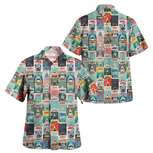 May include: Short-sleeved button-down shirt featuring a repeating pattern of "JAWS" movie posters. The design includes various shark illustrations and the movie title in a grid-like arrangement. The shirt has a relaxed fit and a classic collar.