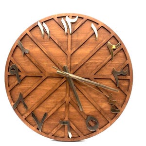 K&ouml;nnte beinhalten: Eine runde Holzuhr mit arabischen Ziffern in Gold. Das Zifferblatt hat eine warme braune Farbe mit einem geometrischen Design. Die Zeiger sind goldfarben und zeigen die Uhrzeit an. Eine dekorative Wanduhr.