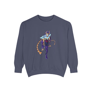May include: A navy blue sweatshirt featuring a colorful graphic of a character with a helmet, cape, and gold chain. The character is depicted in shades of purple, blue, and gold. The sweatshirt has long sleeves and a crew neck.
