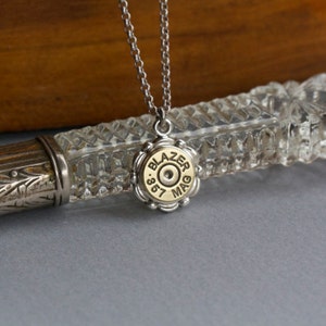 May include: Silver chain necklace with a gold bullet pendant that says "Blazer .357 Mag".