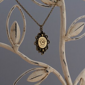 May include: A gold necklace with a brass bullet pendant featuring the inscription "Winchester 45 Colt".