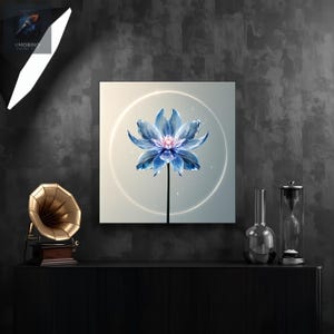 Puede incluir: Impresión en lienzo cuadrada con una flor de loto azul con centro rosa, sobre un fondo suave y brillante. La flor está rodeada por una luz circular blanca. La obra de arte se exhibe sobre una superficie negra.