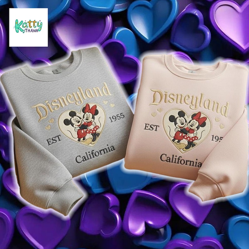 two sweatshirts with the Disney theme park logo, specifically Minnie Mouse, against a background of hearts in various colors, including purple, blue, and pink.