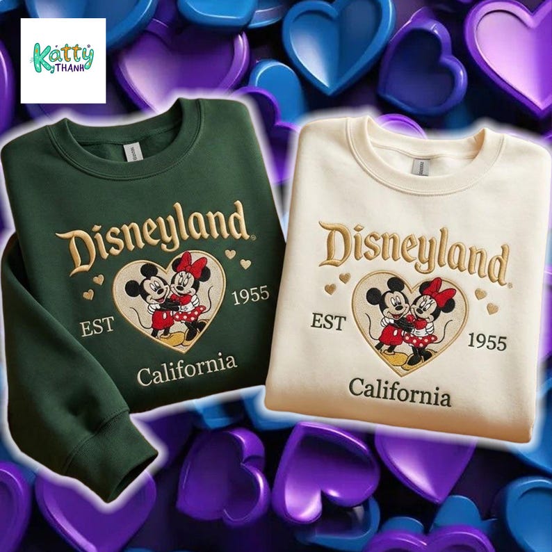 two sweatshirts with the Disney theme park logo and text, set against a background of hearts in various colors.