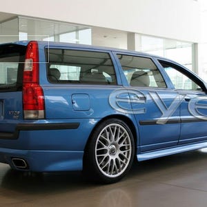 Peut inclure: Un break bleu avec des jantes en alliage argentées est garé à l'intérieur. La voiture a un aileron arrière et des feux arrière rouges. Le véhicule est un modèle Volvo V70 2.0. La voiture est dans une salle d'exposition.