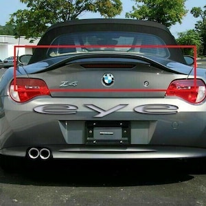 Op de afbeelding: Achteraanzicht van een grijze BMW Z4 cabriolet. De auto heeft een zwart cabriodak, rode achterlichten en een verchroomde uitlaat. Het woord "eye" wordt in chromen letters onder de kofferbak weergegeven.