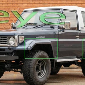 以下が含まれることがあります： 白い屋根の濃いグレーのトヨタランドクルーザーSUV。 車両は大きな黒いオフロードタイヤを備え、左上に緑色の文字で「eye」という文字が見えます。 「Land Cruiser」というテキストが側面に表示されています。