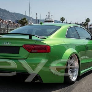 May include: A vibrant green Audi RS5 coupe with a black spoiler, seen on a racetrack. The car features silver alloy wheels and red rear lights. The background shows a crowd, palm trees, and yachts.