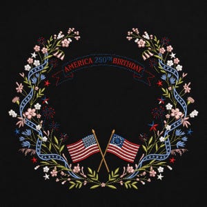 May include: Embroidered wreath design with the text "AMERICA 250TH BIRTHDAY" on a banner. The wreath features flowers, stars, and two crossed American flags. The design is on a black background.