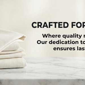 May include: A stack of folded, off-white bed sheets. The sheets are neatly arranged on a marble surface. Text in the image reads: CRAFTED FOR YOUR HOME, Where quality meets comfort. Our dedication to superior textiles ensures lasting beauty.