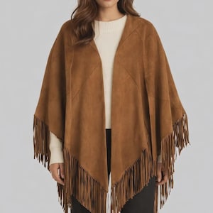 May include: A brown suede poncho with fringe detailing. The open-front poncho features a V-neck design and is a solid brown color. The fringe is along the bottom edge of the poncho.