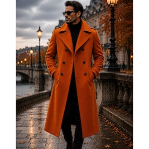 May include: A long, double-breasted orange wool coat featuring wide lapels, shoulder epaulets, and black buttons. The coat is worn over a black turtleneck sweater and black trousers, with the wearer sporting dark sunglasses while standing outdoors.