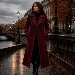 May include: A long, double-breasted coat in a deep burgundy hue, featuring a structured collar, notched lapels, and dark buttons. The coat is worn over a black turtleneck sweater and black trousers, creating a layered look with a textured finish.