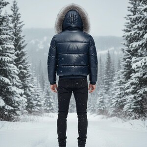 May include: A navy blue puffer jacket with a fur-lined hood. The jacket is worn with black jeans. The person is standing in a snowy forest. The jacket has a quilted design and a zipper closure.