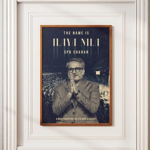 May include: Framed poster with a dark background and the text "THE NAME IS ILAYA NILA SPB CHARAN." The image features a man in a suit with glasses, hands clasped in prayer, and the text "A MAN CARRYING HIS FATHER'S LEGACY."
