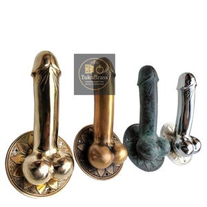 Puede incluir: Cuatro manijas de puerta de latón en diferentes acabados: dorado, bronce, verdín y plateado. Cada manija presenta un diseño fálico con una base redonda. Las manijas están montadas en placas circulares decorativas con motivos florales.