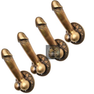 Puede incluir: Cuatro manijas de puerta de latón antiguo, cada una con la forma de un falo estilizado. Las manijas están montadas sobre placas circulares con un diseño floral. El acabado es de color latón envejecido y la estética general es vintage.