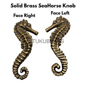 Op de afbeelding: Twee massief messing zeepaardknoppen, één naar rechts en de andere naar links gericht. De knoppen hebben getextureerde schubben en een gebogen staart. De tekst "Solid Brass SeaHorse Knob" en "Face Right" en "Face Left" is zichtbaar.