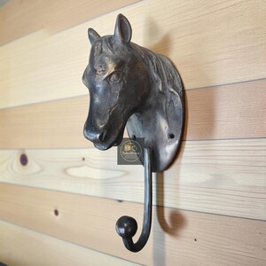 Peut inclure: Un crochet mural en forme de tête de cheval de couleur bronze. Le crochet est en forme de tête de cheval avec un crochet incurvé qui s'étend vers le bas. Le crochet est monté sur un mur en bois. Le crochet est en métal et a une finition sombre et antique.