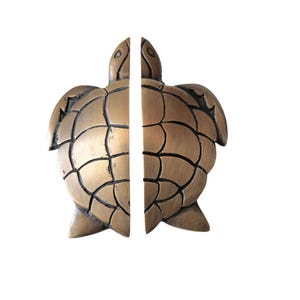 Op de afbeelding: Bronzen boekensteunen in de vorm van een schildpad. Elke boekensteun is de helft van een schildpad, met gedetailleerde schildpatronen en vinnen. De boekensteunen zijn ontworpen om rechtop te staan en een decoratieve touch toe te voegen.