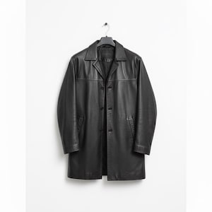 May include: A black leather coat with a button-up front and a collared neckline. The coat is hanging on a black hanger against a white background. The coat has two front pockets.
