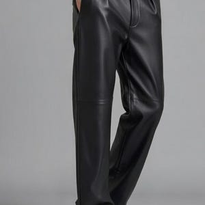 May include: Black leather pants with a high waist and a relaxed fit. The pants have a button closure and pockets. The model is wearing black shoes. The pants are made of a smooth, shiny material.