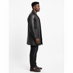 May include: A black leather coat with a button-up front and a collared neckline. The coat is knee-length and worn with black jeans and brown leather boots. The coat appears to be made of a smooth, high-quality leather.