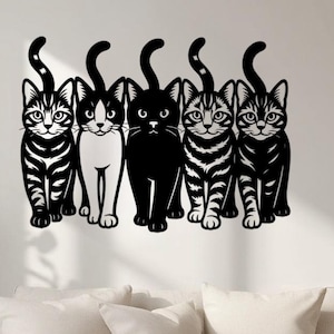Puede incluir: Una decoración de pared de metal negro que representa cinco gatos estilizados con colas curvadas. Los gatos tienen diferentes patrones, incluyendo rayas y colores sólidos, y están dispuestos en una fila. La obra de arte está montada en una pared blanca sobre un sofá.