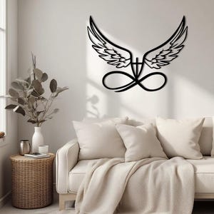 May include: Black metal wall art featuring stylized angel wings above an infinity symbol. The wings are detailed with feather patterns. The artwork is mounted on a white wall above a cream-colored sofa with pillows and a blanket. A decorative piece for home decor.