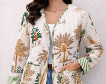 May include: A cream-colored quilted jacket featuring a botanical print with palm trees and fruit motifs. The jacket has a V-neckline, long sleeves with green striped cuffs, two front patch pockets, and green striped trim along the edges.