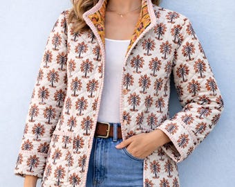 May include: A quilted jacket featuring a cream base with a repeating orange and blue tree pattern, long sleeves, a single button closure, and two front pockets. The interior lining displays a contrasting yellow and orange floral print.