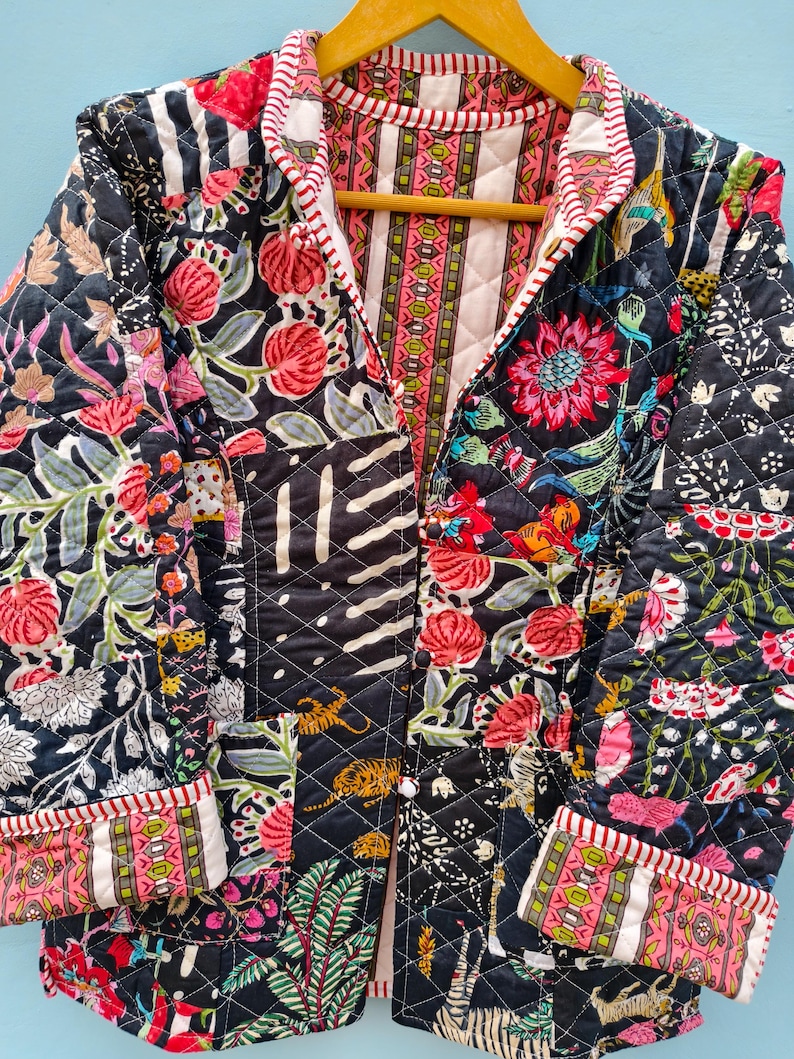 May include: A quilted jacket featuring a patchwork design with a black base and vibrant floral, tiger, and striped patterns in pink, green, and white. The garment has long sleeves, a front button closure, and a red and white striped trim along the edges.