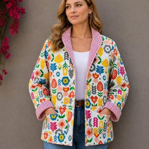May include: A white jacket with a vibrant floral design in yellow, blue, orange, and pink. The jacket has a red and white striped trim and two front pockets. A brown belt is visible.