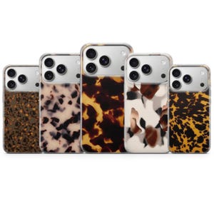 May include: Five rectangular smartphone cases arranged in a row, each featuring a distinct tortoiseshell or animal-inspired pattern in shades of brown, black, cream, and amber. Each case has a clear upper section with cutouts for camera lenses.