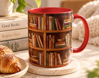 May include: A ceramic mug with a bright red interior and handle, featuring a wrap-around illustration of a wooden bookshelf filled with various colourful books, small decorative objects, and a tiny potted plant across three distinct shelves.