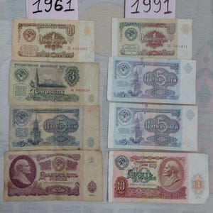 May include: A collection of Soviet Union banknotes from 1961 and 1991. The notes, in denominations of 1, 3, 5, 10, and 25 roubles, feature Cyrillic text and historical imagery. The image includes the years 1961 and 1991.