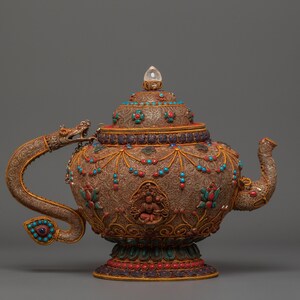Peut inclure: Théière antique ornée avec des détails complexes. Le corps en métal marron est orné de pierres précieuses turquoise et rouges, d'accents dorés et d'une poignée en forme de dragon. Un cristal clair est posé sur le couvercle. Un objet décoratif unique.