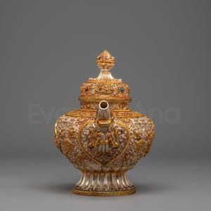 Può includere: Teiera ornata in argento e oro con intricati disegni floreali e a forma di cuore. La teiera presenta un coperchio dettagliato con un terminale ed è adornata con piccole pietre preziose. Il beccuccio e la base sono anch'essi impreziositi da accenti dorati.