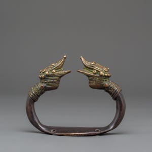 May include: An antique bronze handle featuring two stylized dragon heads facing each other. The handle has a curved, dark brown bar with mounting holes. The dragon heads are detailed with textured scales and open mouths, showcasing a vintage aesthetic.