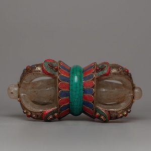 May include: An ornate, symmetrical object with a clear, curved central section. The object features intricate metalwork with red, blue, and green accents, and a central turquoise-colored band. Clear, rounded end pieces complete the design.