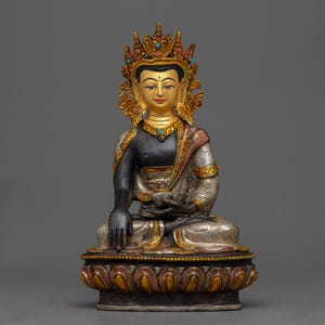 Peut inclure: Statue de Bouddha assis avec une couronne et des accents dorés. La statue a un torse noir, des robes dorées et argentées, et est assise sur une base de fleur de lotus. Des pierres turquoises ornent la couronne et le collier. Représentation de l'art bouddhiste.