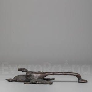May include: Bronze-toned door handle with an artistic design. The handle features a detailed sculpture of a reclining figure with an elongated arm, creating a unique and decorative element for doors or furniture.