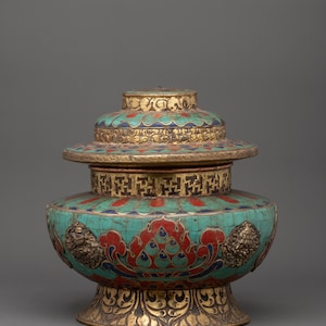May include: An ornate, multi-tiered vessel with a turquoise, red, and gold color scheme. The vessel features intricate patterns and decorative elements, including floral designs and lion-like figures. The base is a pedestal design.