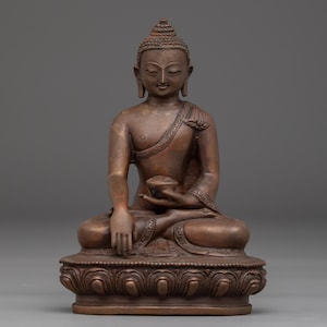 Peut inclure: Statue de Bouddha en bronze en position de méditation assise. La figure a une expression sereine, avec les yeux fermés et un léger sourire. La statue est détaillée avec des motifs complexes sur les vêtements et la base. Le Bouddha tient un petit bol dans sa main gauche.