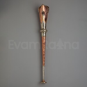 May include: A handcrafted torch with a copper and silver design. The top is copper with a decorative silver band and a silver base. The torch has a long, slender copper shaft and a silver base. The text "Evam Raana" is visible in the image.