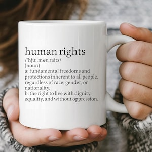 May include: White ceramic mug with the words "human rights" and its definition printed in black. The definition includes the phrase "fundamental freedoms and protections inherent to all people, regardless of race, gender, or nationality."