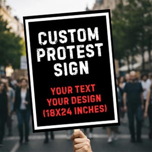 May include: A black protest sign with white and red text. The sign reads "CUSTOM PROTEST SIGN" at the top, with "YOUR TEXT YOUR DESIGN" below. The dimensions are listed as 45x61 cm. The sign is held up in a crowd.