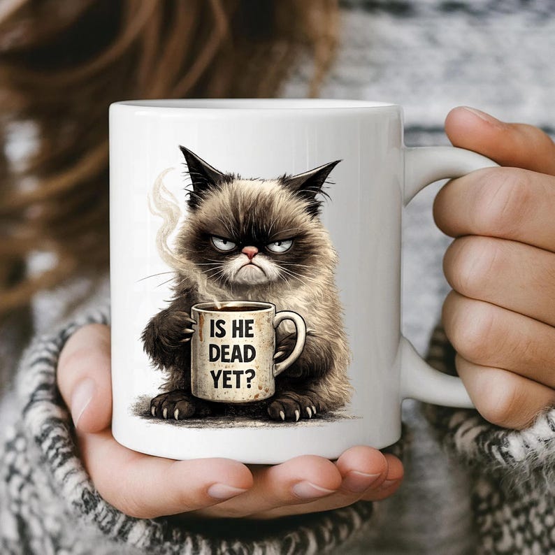 May include: White ceramic mug featuring a grumpy cat illustration holding a coffee cup. The mug has the text "IS HE DEAD YET?" printed on it. The cat is depicted with a stern expression and steam rising from the coffee.